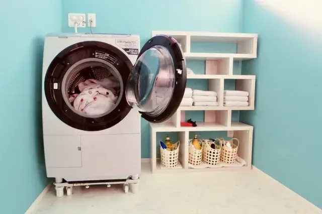 ドラム式洗濯機と棚にバスタオルが畳まれて置かれている画像