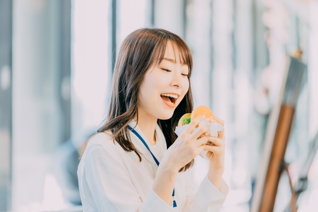 ハンバーガーを食べる女性の画像
