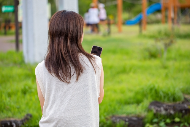 公園で携帯電話を操作する女性の画像
