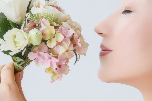 女性が花束の香りを嗅いでいる画像